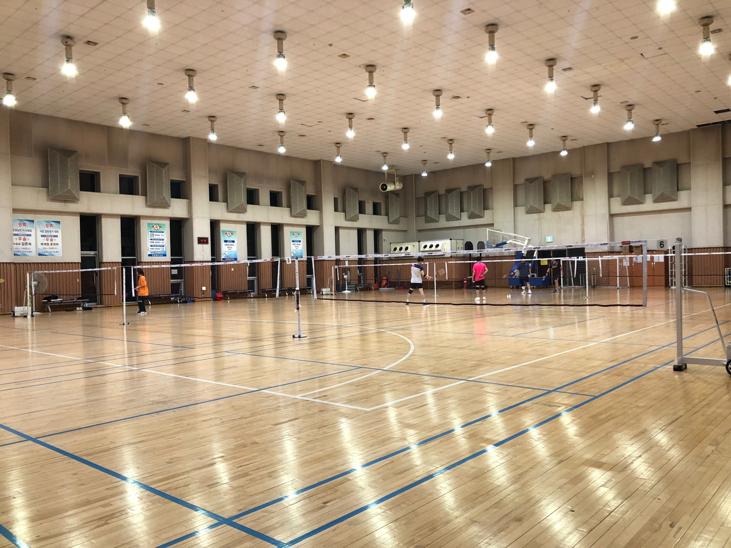 체육관 내부 전경이며, 6코트로 구성되어 있고 배드민턴을 치는 회원들 모습입니다.