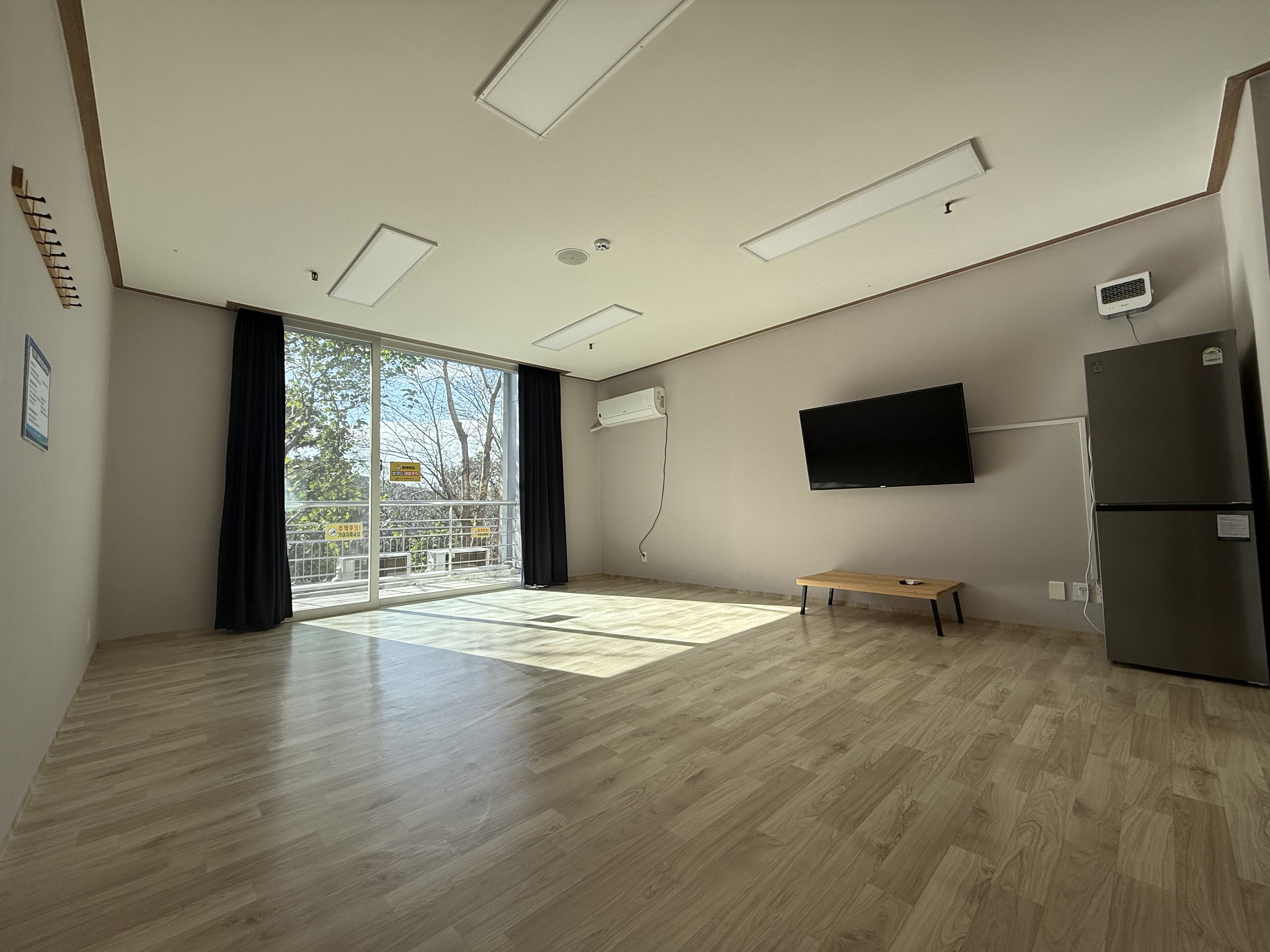 생활관 내부이며, 산이 보이는 창문이 중앙에 있고 에어컨이 비치되어 있으며 장판이 깔려있는 모습