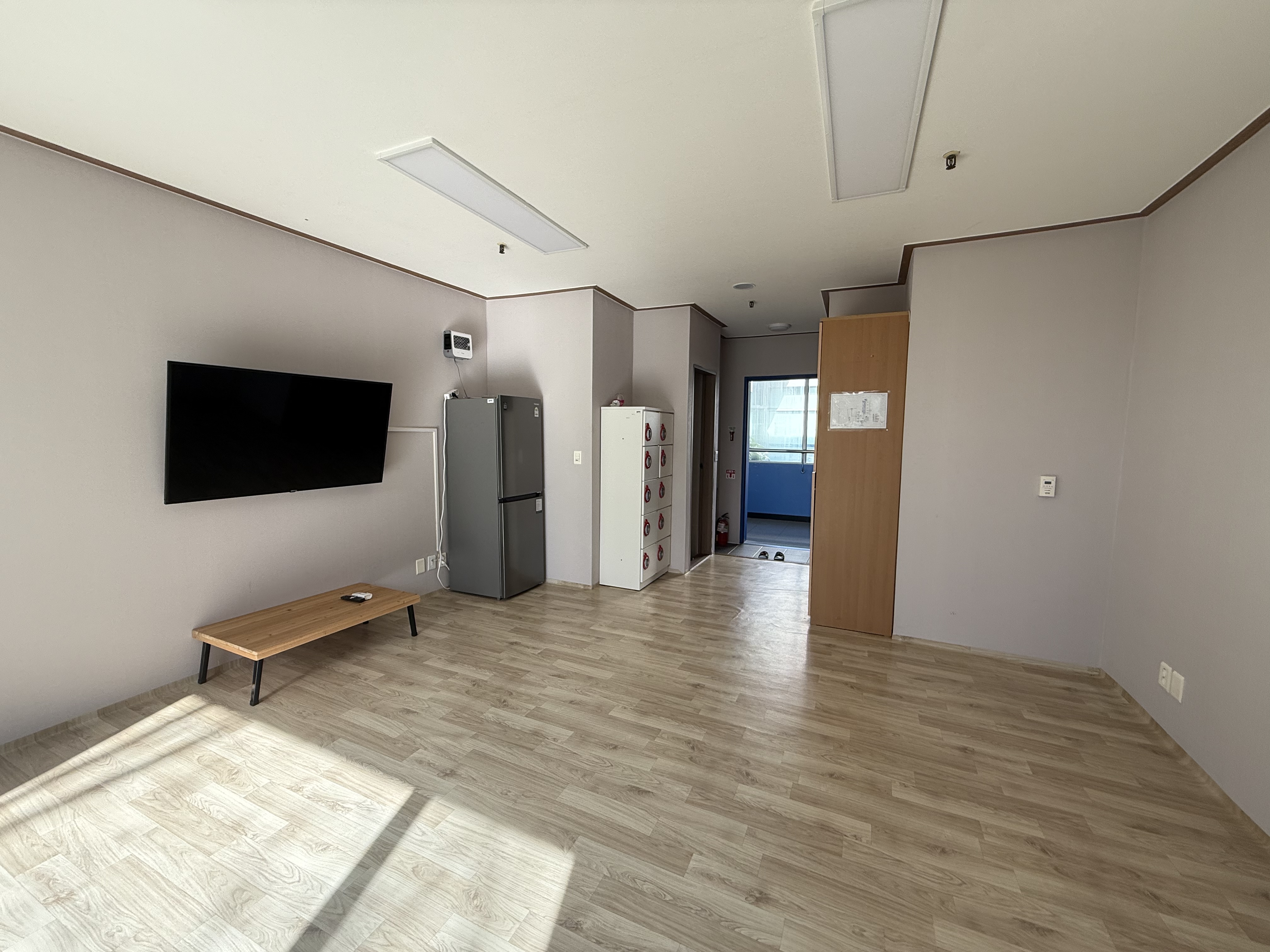 생활관 내부이며, 출입구 통로를 따라 신발장과 다목적함이 비치되어 있고 장판이 깔려있는 모습