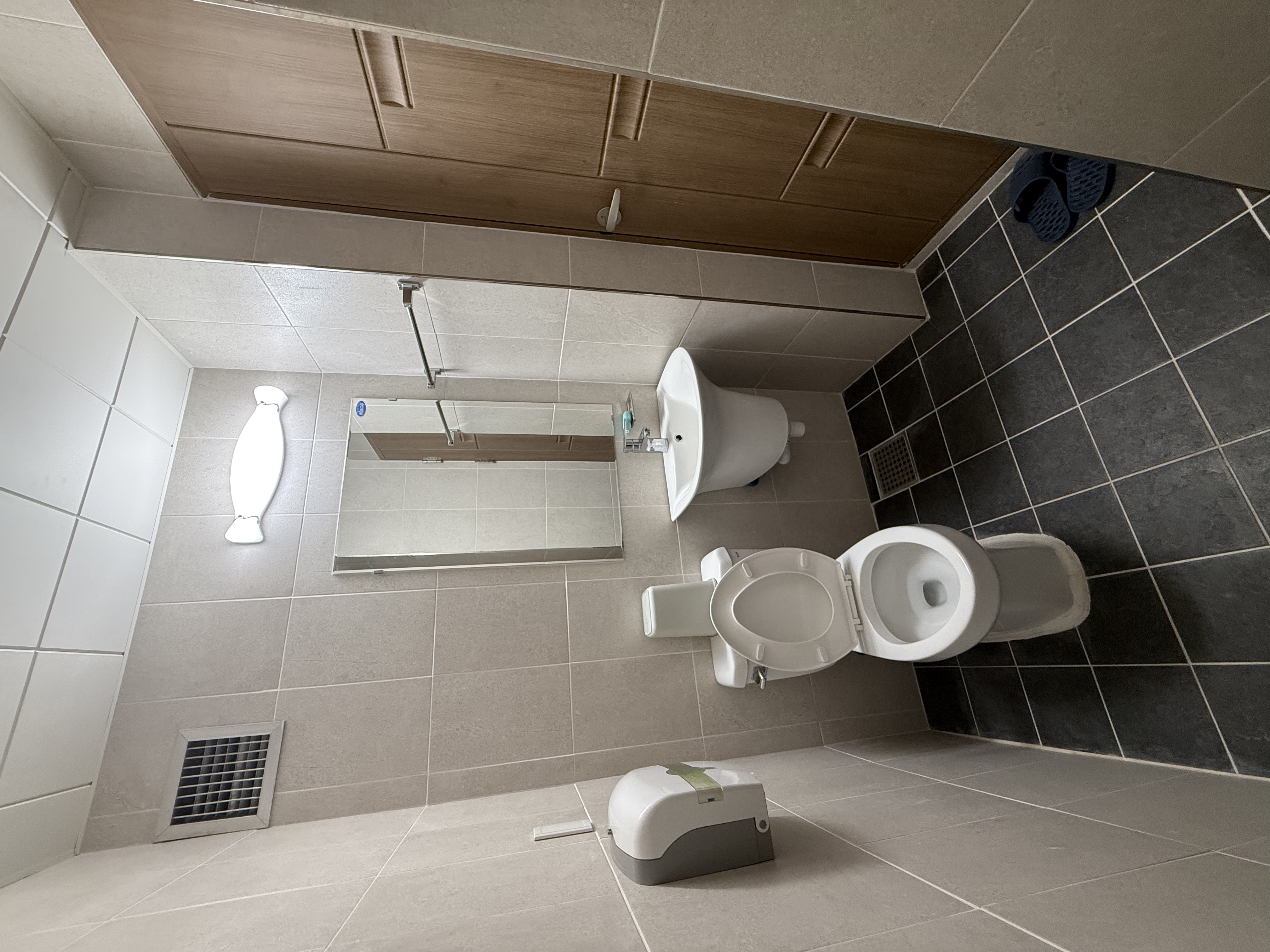 생활관 내 화장실 내부이며, 거울과 세면대, 양변기 및 휴지가 비치되어있는 모습